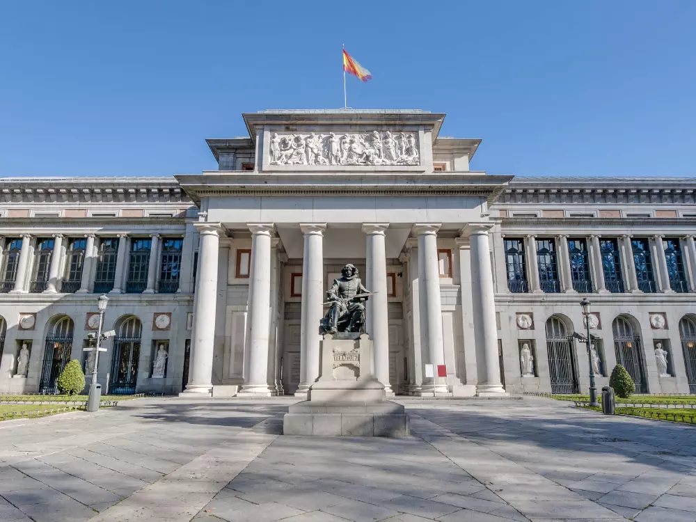 Imagen de una galeria del museo de Prado con cuadros de grandes pintores de la historia de europa a ambos lados de la galeria